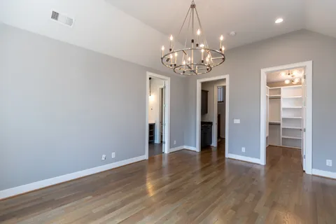a view of a big room with wooden floor chandelier and windows