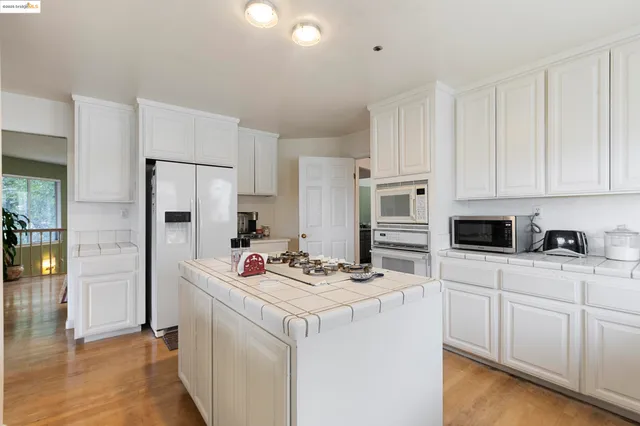 a kitchen with stainless steel appliances kitchen island granite countertop a refrigerator sink and white cabinets