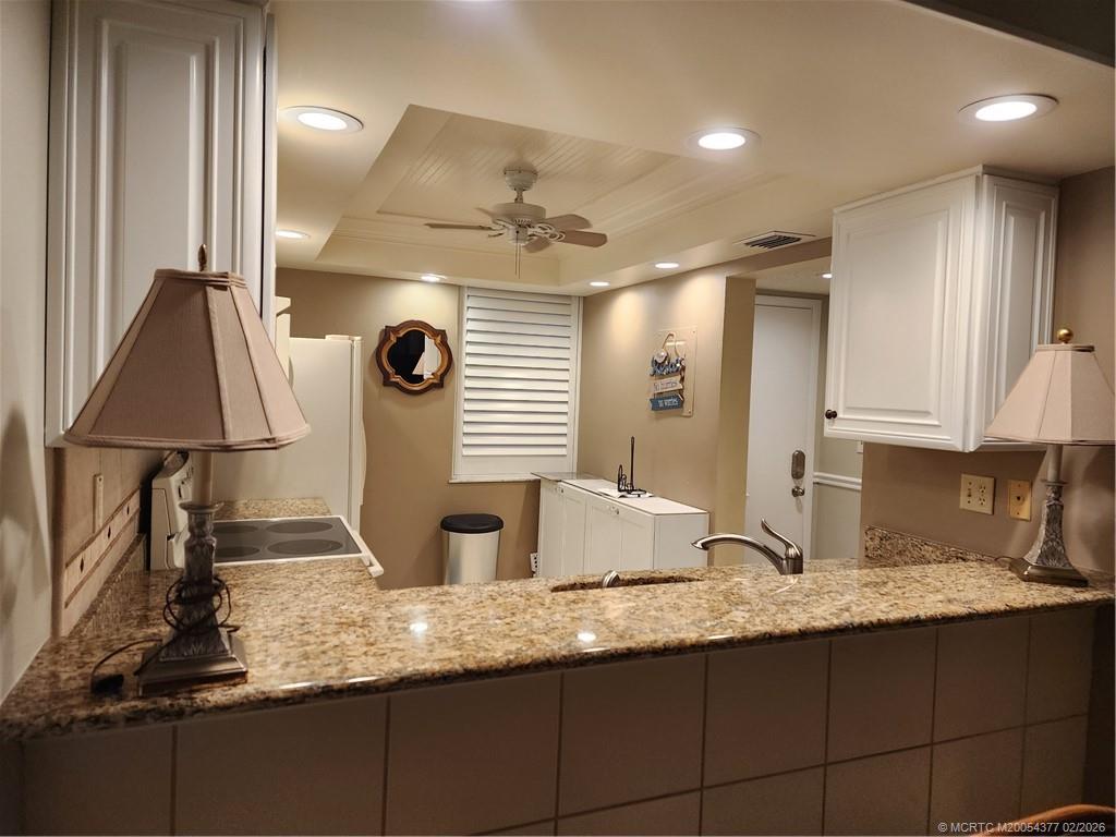 1950 Southwest Palm City Road, Unit 13102 Stuart, FL 34994 - Photo 14 of 40 a kitchen with granite countertop a sink a stove and a wooden floor
