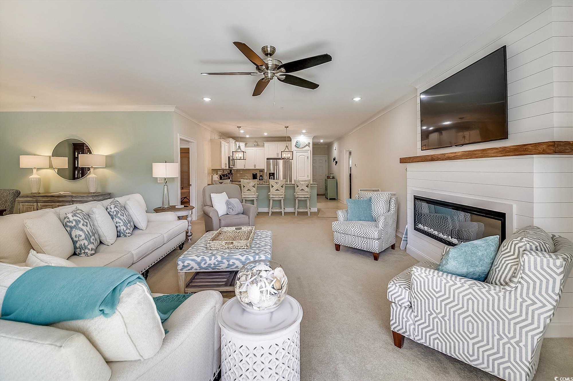 1029 Ray Costin Way, Unit VILLA 906 Murrells Inlet, SC 29576 - Photo 6 of 40 Living area featuring ceiling fan, ornamental molding, light carpet, a glass covered fireplace, and recessed lighting