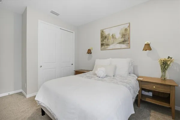 a bedroom with a bed and a lamp on dresser