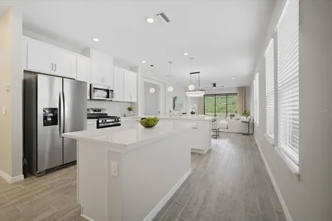 a kitchen with stainless steel appliances a refrigerator a stove a sink dishwasher a oven with white cabinets and wooden floor