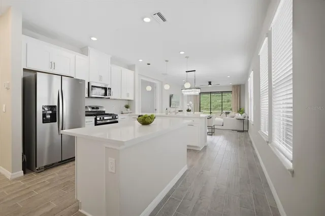 a kitchen with stainless steel appliances a refrigerator a stove a sink dishwasher a oven with white cabinets and wooden floor