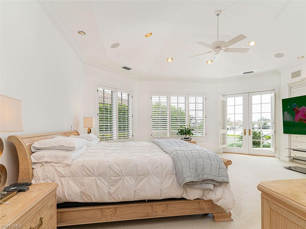 330 Devils Bight Naples, FL 34103 - Photo 27 of 47 a bedroom with a large bed and a flat tv screen on dresser