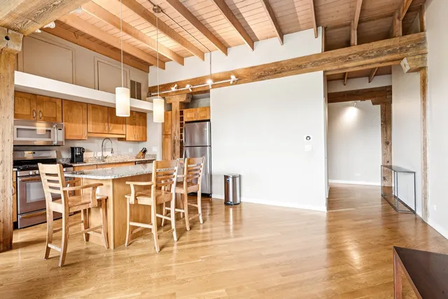 a kitchen with stainless steel appliances kitchen island granite countertop a table and chairs in it