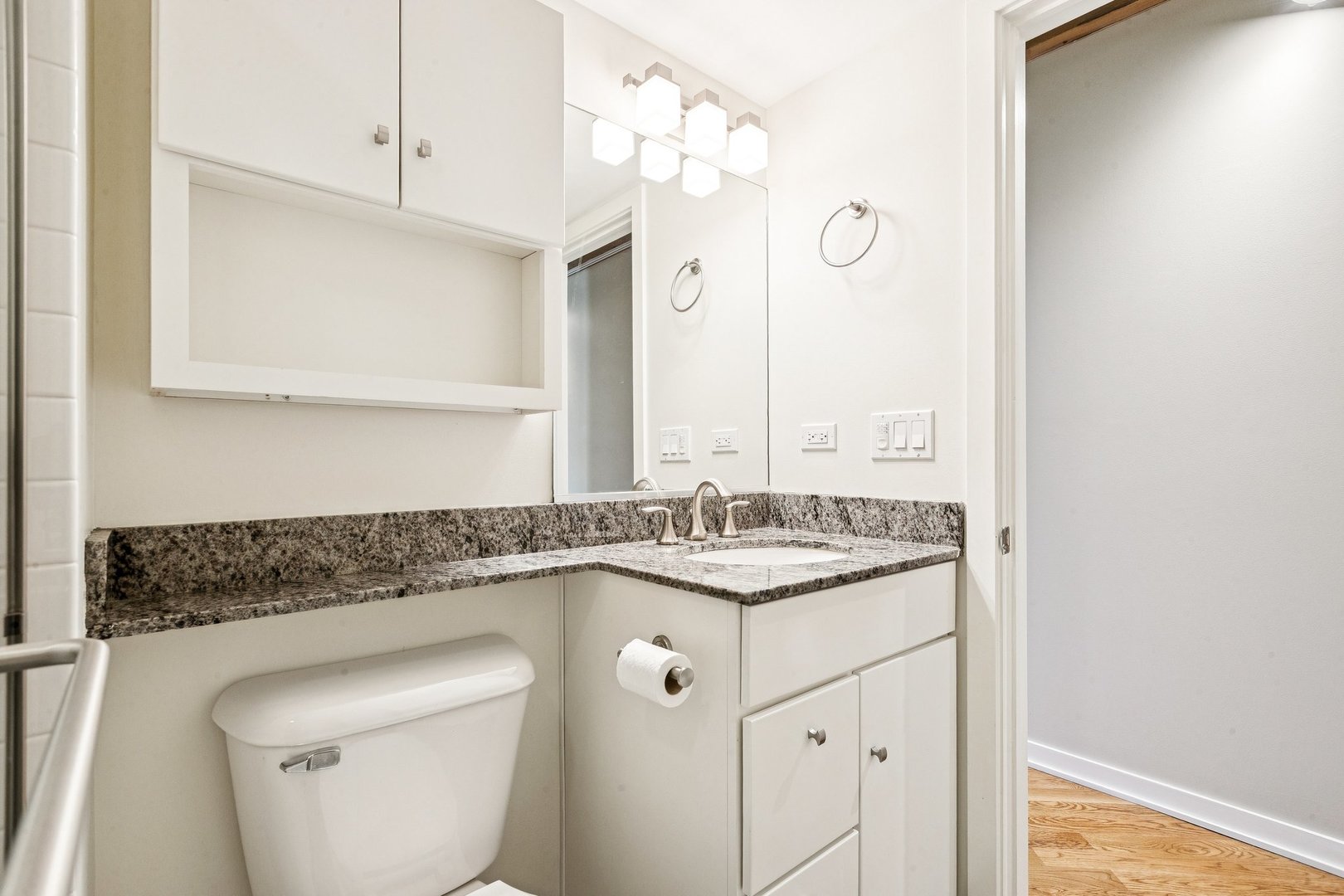 3201 North Ravenswood Avenue, Unit 301 Chicago, IL 60657 - Photo 25 of 38 a bathroom with a granite countertop sink a toilet and a mirror