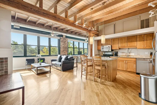 a dining hall with stainless steel appliances kitchen island granite countertop a dining table chairs and view of living room