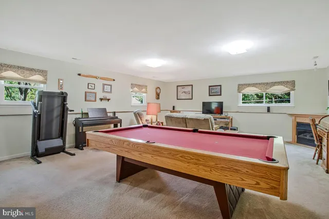 a living room with furniture pool table and windows