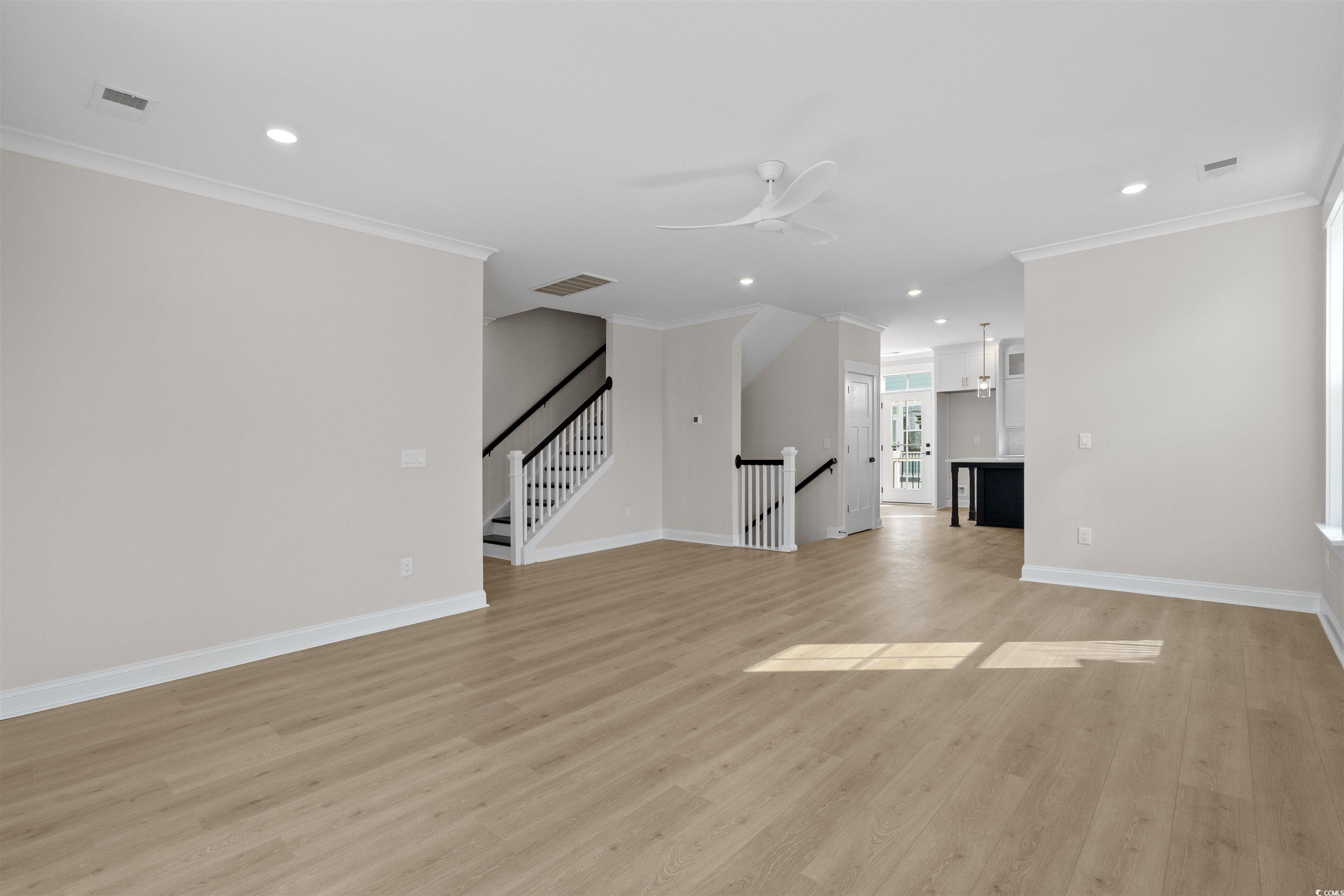 8476 Duke Place, Unit 32 Myrtle Beach, SC 29572 - Photo 14 of 40 Unfurnished living room with light wood finished floors, recessed lighting, crown molding, ceiling fan, and stairway