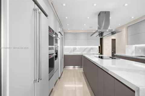 a large kitchen with stainless steel appliances kitchen island a large counter top and a refrigerator