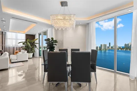 a view of a dining room with furniture a chandelier and large window