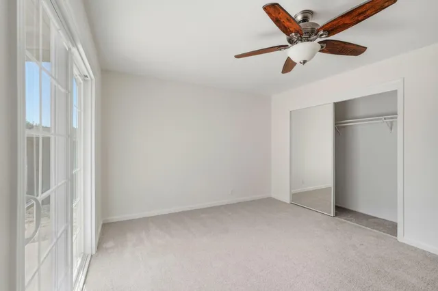 an empty room with a ceiling fan and a window