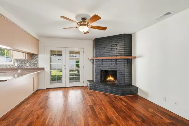 a living room with stainless steel appliances wooden floor and a fireplace