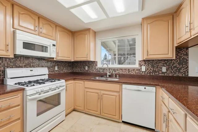 a kitchen with cabinets appliances a sink and a window