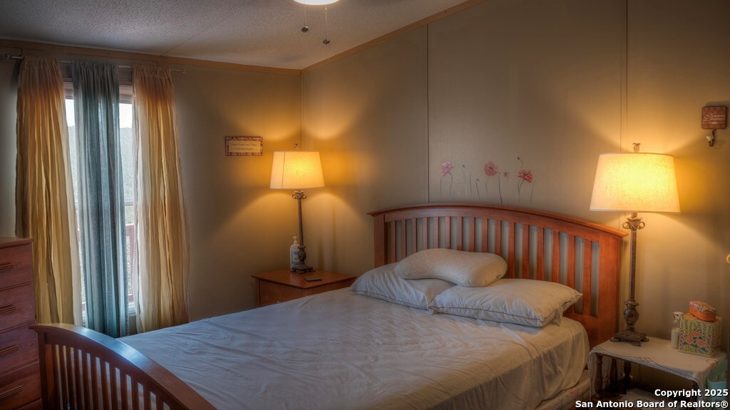 560 Pine Mountain Road Camp Wood, TX 78833 - Photo 18 of 38 a bedroom with a bed and a chandelier