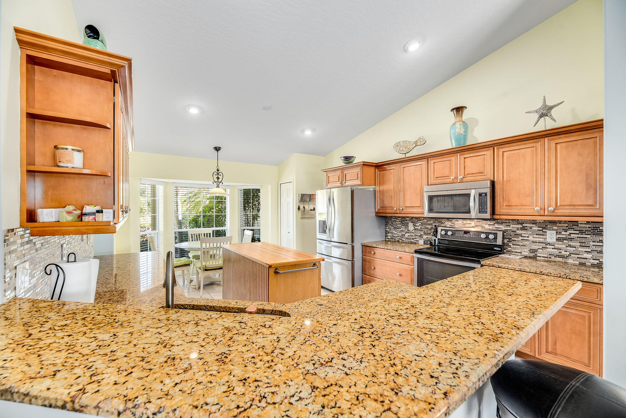 1566 Eagles Circle Sebastian, FL 32958 - Photo 17 of 74 a kitchen with stainless steel appliances kitchen island granite countertop a refrigerator stove oven dining table and chairs with wooden floor