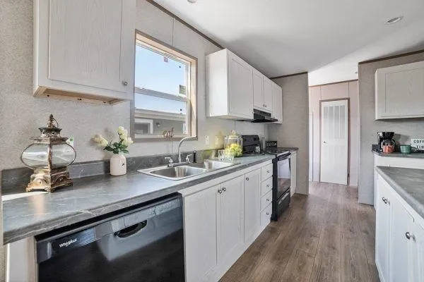 a kitchen with stainless steel appliances white cabinets a sink dishwasher a stove and white cabinets next to a window