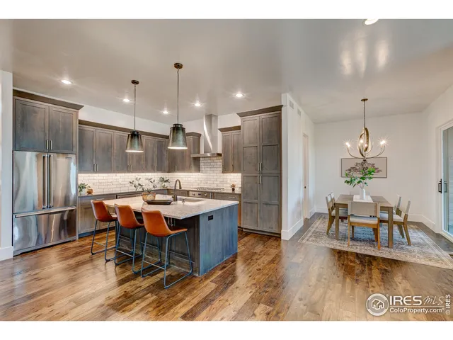 a kitchen with stainless steel appliances kitchen island granite countertop a table chairs and a refrigerator