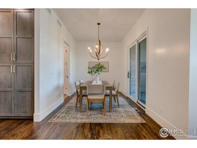 a dining room with wooden floor a chandelier a wooden table and chairs