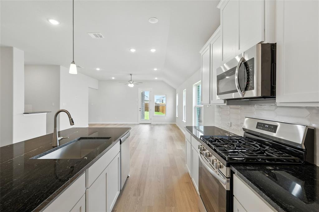 530 Red Barn Drive Van Alstyne, TX 75495 - Photo 6 of 40 Kitchen featuring appliances with stainless steel finishes, light wood-style flooring, vaulted ceiling, tasteful backsplash, and white cabinetry