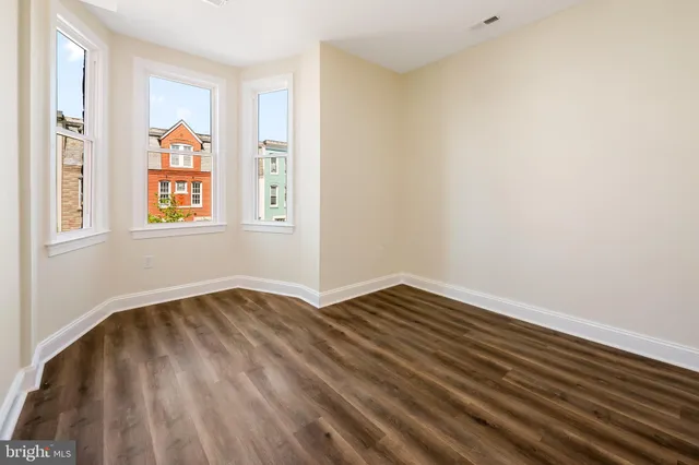 a view of an empty room with window and wooden floor