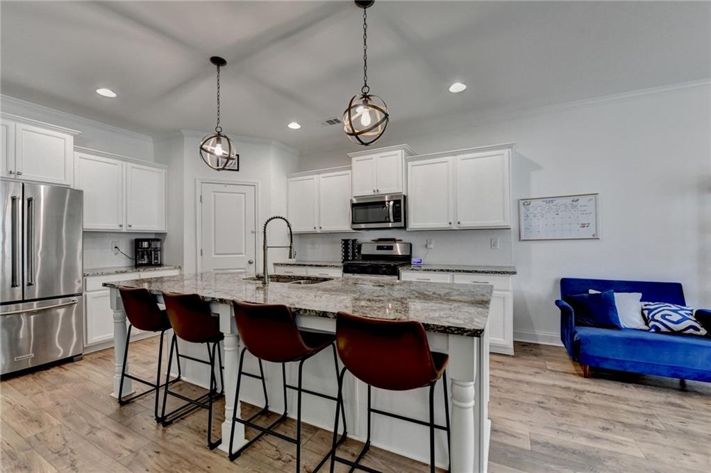 2129 Charmond Drive Monroe, GA 30656 - Photo 7 of 37 a kitchen with stainless steel appliances granite countertop a sink a stove a refrigerator and island with wooden floor