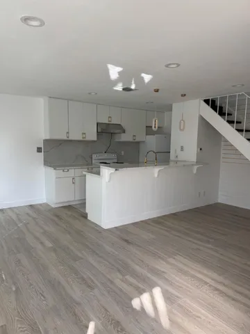 a view of a kitchen with a sink and dishwasher a refrigerator with wooden floor