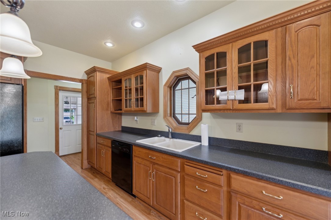 45230 Cemetery Road Wellington, OH 44090 - Photo 12 of 50 Kitchen with black appliances, a sink, dark countertops, light wood finished floors, and brown cabinets