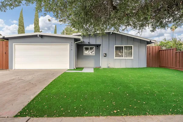 a view of a kitchen counter top space with sink stainless steel appliances and living room view