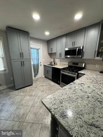 a kitchen with stainless steel appliances kitchen island granite countertop a sink stove and refrigerator