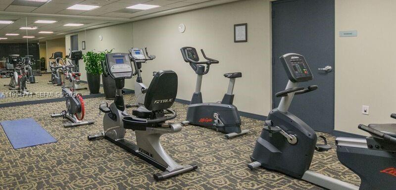 901 Brickell Key Boulevard, Unit 3102 Miami, FL 33131 - Photo 47 of 56 a room with gym equipment and mirror