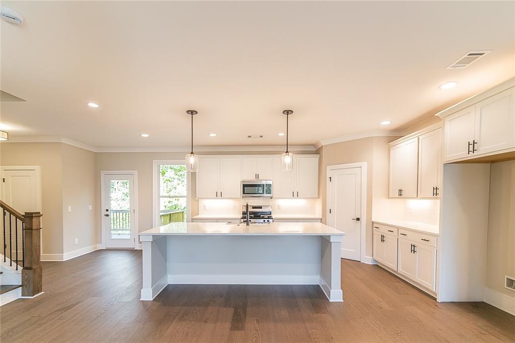 2462 Waldrop Ridge Court Decatur, GA 30034 - Photo 4 of 20 a large kitchen with kitchen island a stove a sink a refrigerator and white cabinets with wooden floor