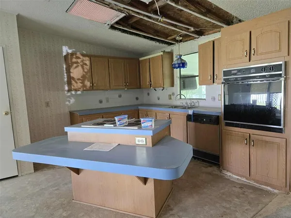 a kitchen with kitchen island granite countertop a sink cabinets and stainless steel appliances
