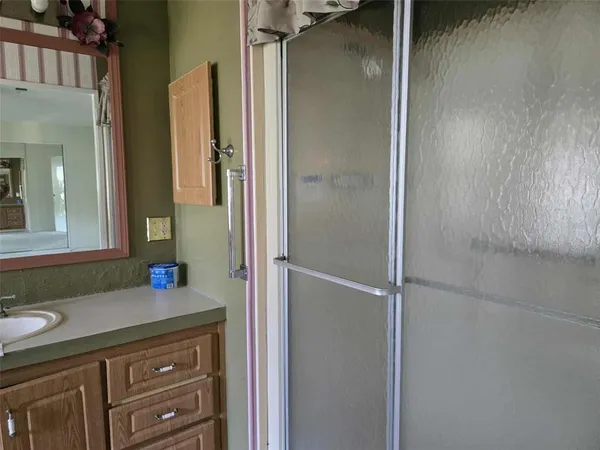 a bathroom with a granite countertop shower sink vanity and mirror