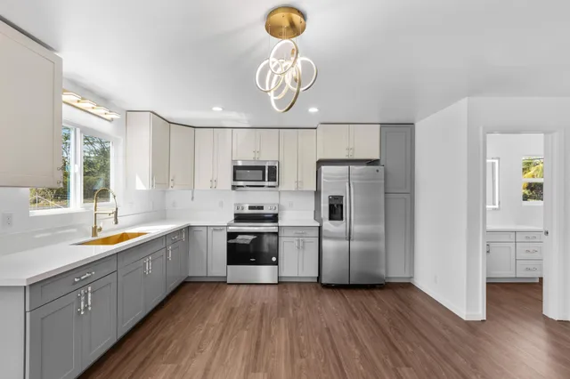 a kitchen with stainless steel appliances granite countertop a sink a stove a refrigerator cabinets and wooden floor