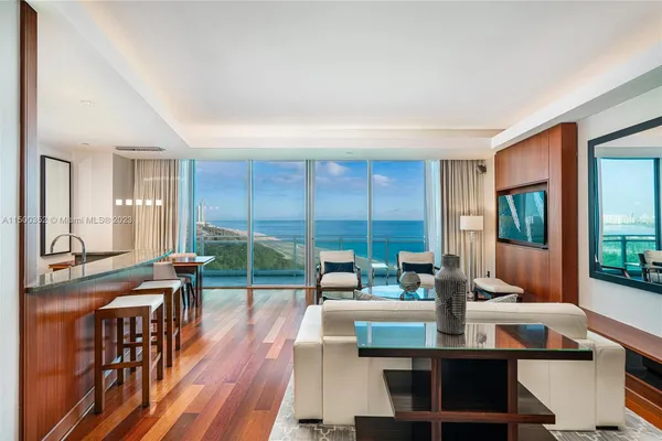 a living room with furniture a large window and wooden floor