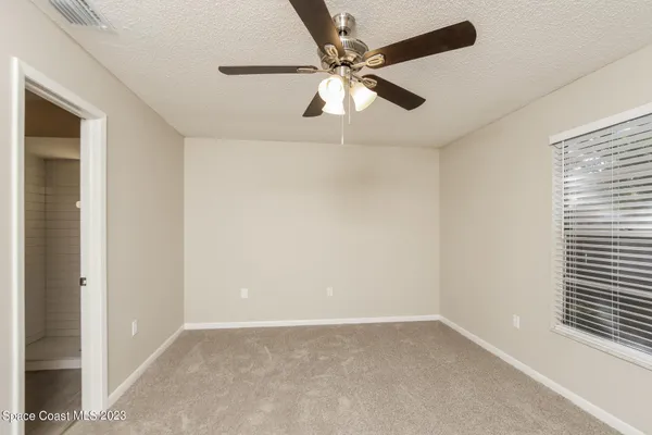 an empty room with windows and fan
