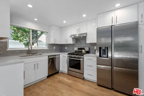 a kitchen with stainless steel appliances granite countertop a refrigerator a sink a stove and a refrigerator