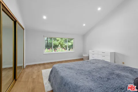 a view of a bedroom with wooden floor and window