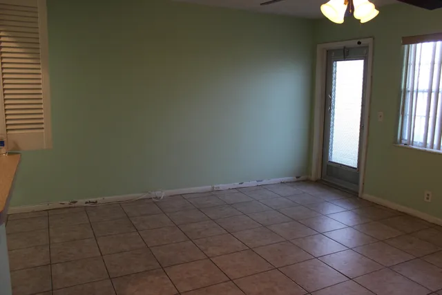 an empty room with windows and fan