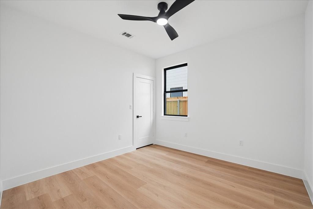 1652 West Wintergreen Road Lancaster, TX 75134 - Photo 20 of 25 Neutral wall tones, wood-finish flooring, a modern black ceiling fan with integrated lighting, and a black-framed window