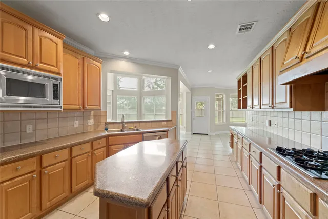 a large kitchen with stainless steel appliances granite countertop a large stove top oven a sink dishwasher and cabinets with wooden floor