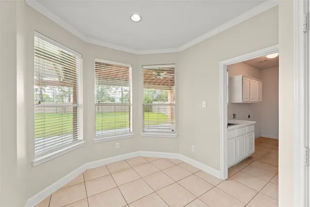 a view of an empty room with a window and a kitchen