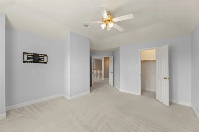 a view of an empty room with chandelier fan
