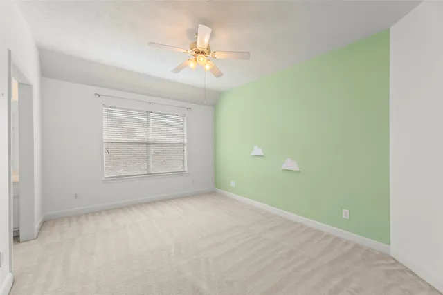 an empty room with chandelier fan and windows