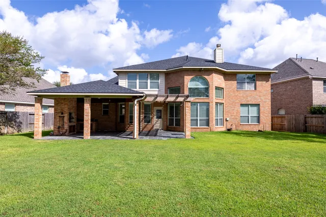 a view of a brick house with a big yard and large trees