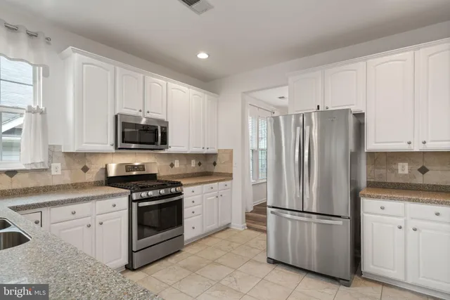 a kitchen with white cabinets white stainless steel appliances and sink