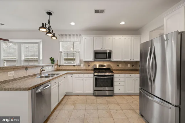 a kitchen with granite countertop a refrigerator oven a sink and dishwasher
