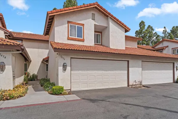 a white house with a small yard and parking space