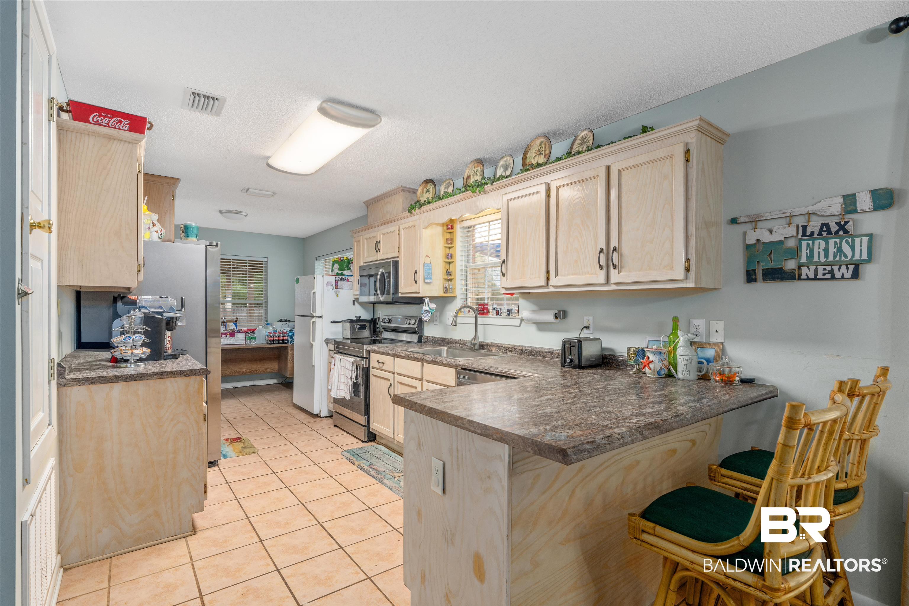 23186 Pecan Street Robertsdale, AL 36567 - Photo 6 of 36 Kitchen featuring light brown cabinets, light tile patterned floors, a breakfast bar area, a peninsula, and stainless steel appliances
